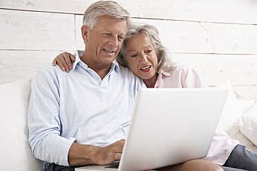Spanien, älteres Ehepaar, das lächelnd E-Mails auf dem Laptop prüft - PDYF000121