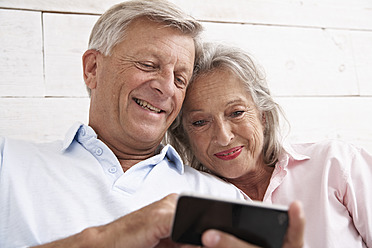 Spanien, Älteres Ehepaar mit Mobiltelefon, lächelnd - PDYF000124