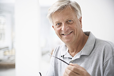 Spain, Senior man holding glasses, smiling, portrait - PDYF000148