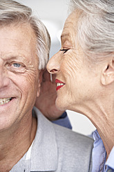 Spanien, ältere Frau flüstert einem Mann ins Ohr, lächelnd - PDYF000156