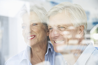 Spain, Senior couple behind window, smiling - PDYF000177