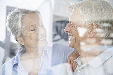 Spain, Senior couple behind window, smiling - PDYF000179