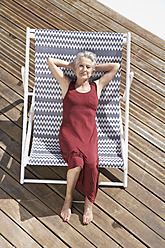 Spanien, Ältere Frau entspannt sich auf einem Liegestuhl am Strand - PDYF000198