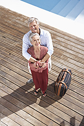 Spanien, älteres Paar mit Koffer am Schwimmbad, lächelnd, Porträt - PDYF000193