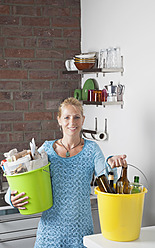 Deutschland, Köln, Ältere Frau trägt Eimer mit Hausmüll in Küche - GWF002002