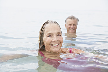 Spanien, Seniorenpaar beim Schwimmen im Meer - PDYF000248