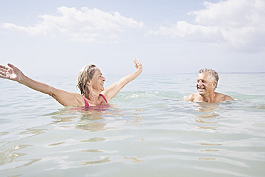 Spanien, Seniorenpaar beim Schwimmen im Meer - PDYF000242