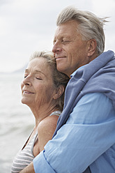 Spain, Senior couple on beach at Atlantic, smiling - PDYF000222