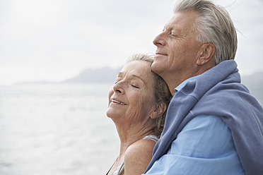 Spain, Senior couple on beach at Atlantic, smiling - PDYF000221