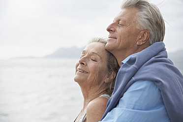 Spanien, Älteres Paar am Strand am Atlantik, lächelnd - PDYF000221