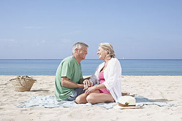 Spanien, Seniorenpaar am Strand sitzend - PDYF000213