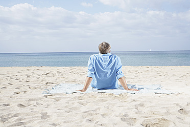 Spanien, älterer Mann sitzt am Strand - PDYF000212