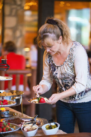 USA, Texas, Ältere Frau steht am Buffet, lizenzfreies Stockfoto