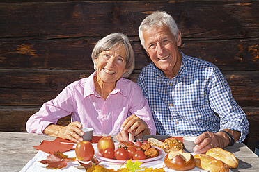 Deutschland, Bayern, Älteres Paar bei der Brotzeit auf einer Berghütte - TCF002979