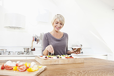 Germany, Bavaria, Munich, Woman preparing pizza in kitchen - RBYF000236