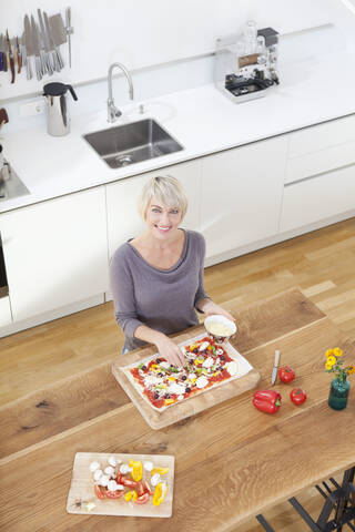 Deutschland, Bayern, München, Frau bereitet Pizza in Küche vor, lizenzfreies Stockfoto