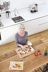 Deutschland, Bayern, München, Frau bereitet Pizza in Küche vor - RBYF000239