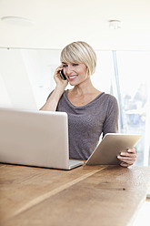 Germany, Bavaria, Munich, Woman working with digital tablet and talking on phone - RBYF000253