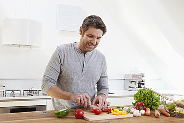 Germany, Bavaria, Munich, Man chopping vegetables in kitchen - RBYF000255