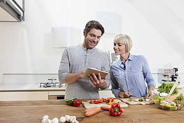 Germany, Bavaria, Munich, Mature couple preparing food while looking digital tablet - RBYF000258