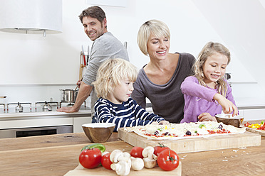 Deutschland, Bayern, München, Familie bereitet Pizza in der Küche zu - RBYF000298