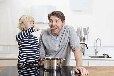 Germany, Bavaria, Munich, Son feeding father in kitchen - RBYF000300