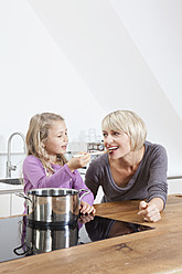 Germany, Bavaria, Munich, Daughter feeding mother in kitchen, smiling - RBYF000305