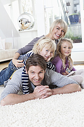 Germany, Bavaria, Munich, Family lying on floor, portrait, smiling - RBYF000312