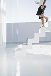 Spain, Mid adult man walking down stairway with cup - WESTF018901