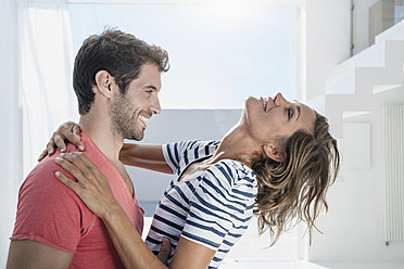 Spain, Mid adult couple embracing each other in modern apartment - WESTF018918