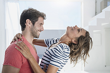 Spanien, Mid adult couple embracing each other in modern apartment - WESTF018918