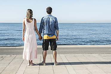 Spain, Mid adult couple standing at Atlantic Ocean, looking at view - WESTF018975