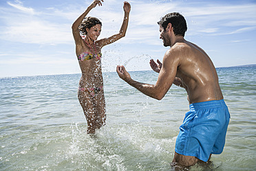 Spanien, Mittleres erwachsenes Paar spielt am Strand - WESTF018999