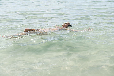 Spain, Mid adult woman swimming in beach - WESTF019001