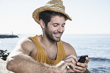 Spanien, mittelgroßer erwachsener Mann mit Smartphone, lächelnd - WESTF019034