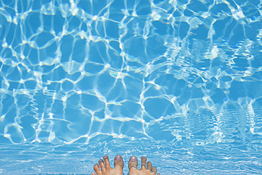 Italy, Womans feet at pool edge, toe dipping in to water - GWF002011