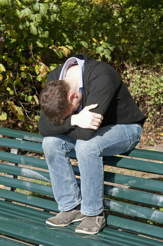 Deutschland, Berlin, Depressiver Mann sitzt auf Parkbank, lizenzfreies Stockfoto