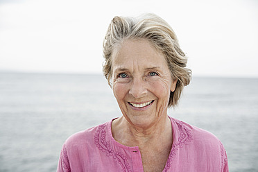 Spain, Senior woman smiling at Atlantic ocean - WESTF019048