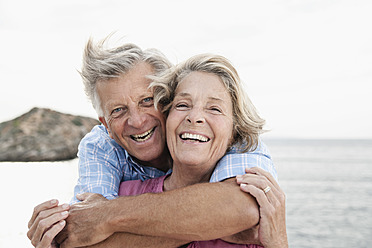 Spain, Senior couple embracing at harbour, smiling - WESTF019050