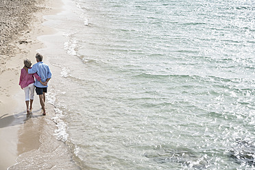 Spanien, Seniorenpaar geht am Strand spazieren - WESTF019069