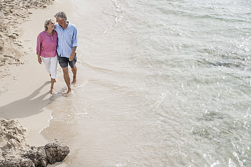 Spanien, Seniorenpaar geht am Strand spazieren - WESTF019070