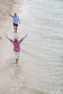 Spanien, Seniorenpaar geht am Strand spazieren - WESTF019072