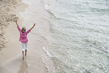 Spanien, Ältere Frau geht am Strand spazieren - WESTF019075