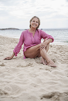 Spanien, Ältere Frau sitzt am Strand - WESTF019079