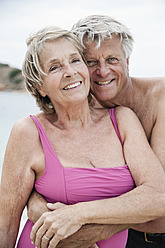 Spanien, Älteres Paar umarmt sich am Strand - WESTF019096