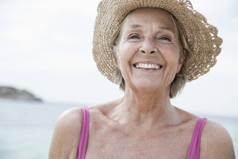 Spain, Senior woman with straw hat on beach stock photo