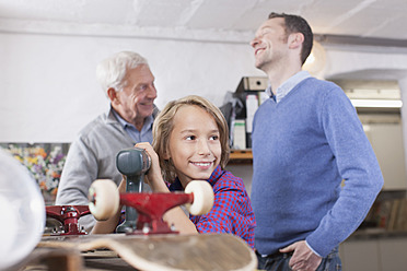 Germany, Leipzig, Grandfather, father and son repairing skateboard - BMF000588