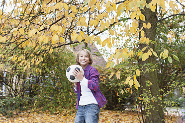 Germany, Leipzig, Boy playing football under autume tree - BMF000623