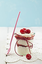 Milk rice pudding with raspberries and jam in glass on table - ECF000154