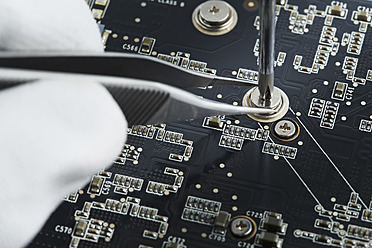 Human hand repairing printed circuit board, close up - DSCF000008